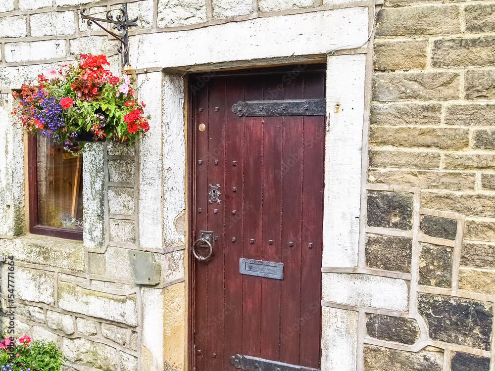 Old-fashioned front door with hanging basket on exterior of stone house wall