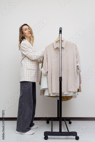 Elegant woman near minimalist slow fashion Clothes rack.