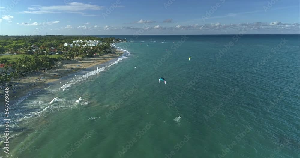 Many kite boarders in the water and many people on the beach. Everyone went to the beach at sunset time. People ride kite boards in the sunset.The camera quickly flies over the athlete. Golden hour Many kite boarders in the water and many people on the beach. Everyone went to the beach at sunset time. People ride kite boards in the sunset.The camera quickly flies over the athlete. Golden hour