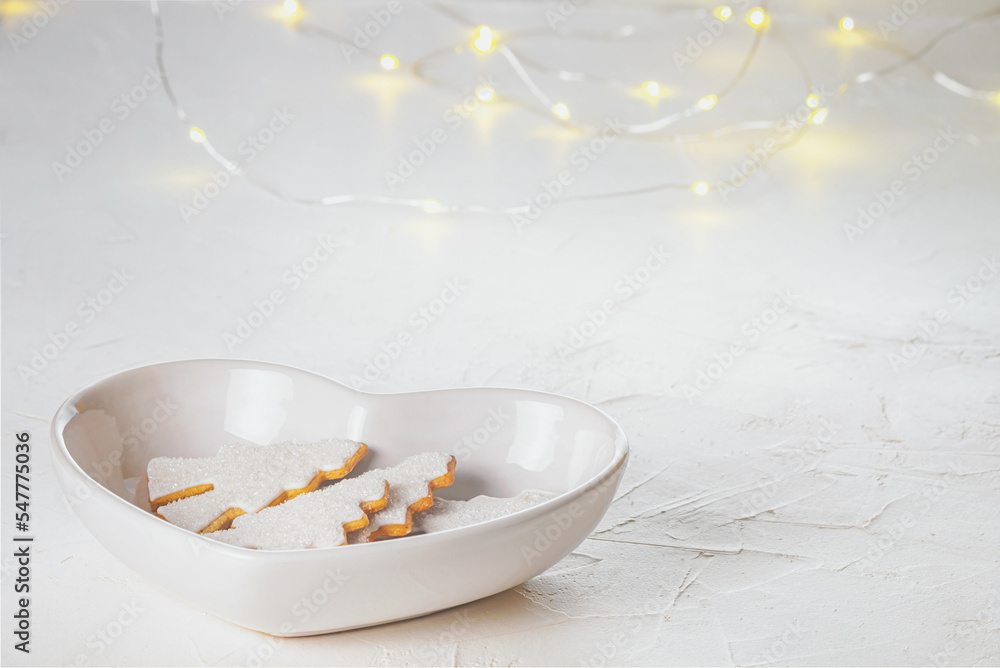 Gingerbread christmas trees in a faience white bowl in the form of heart on a concrete surface, close-up view. Christmas celebration concept with space for text Gingerbread christmas trees in a faience white bowl in the form of heart on a concrete surface, close-up view. Christmas celebration concept with space for text