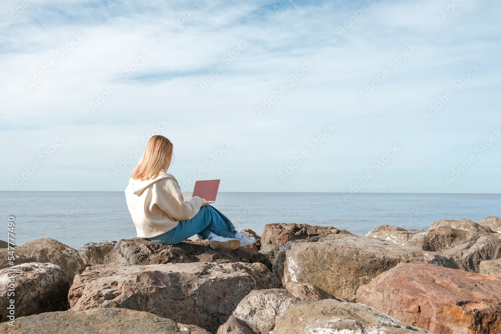 Remote work.Girl freelancer works remotely on the sea shore. workation, remote work,WFVH,Van Life vibes work from vacation home,work travel,remotely work.Travelling.Work from vacation remotely