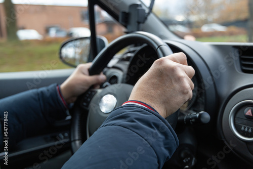 Male hands hold the steering wheel in a Toyota car.
