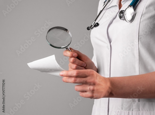 Medical research, analysis concept. Doctor analyzing medicine document with magnifying glass, lens closeup