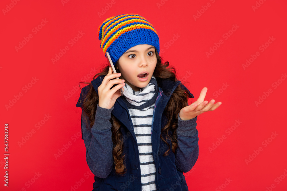 shocked teen girl in down vest with smartphone. portrait of child greeting while phone conversation. shocked teen girl in down vest with smartphone. portrait of child greeting while phone conversation.