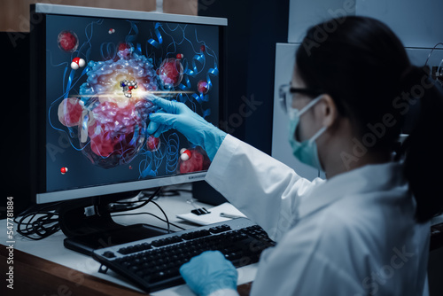 Researcher woman indicates the position of drug sample in the modelling simulation of drug development as shown on a computer monitor. The analytical computer is a supercomputer for drug simulation. photo