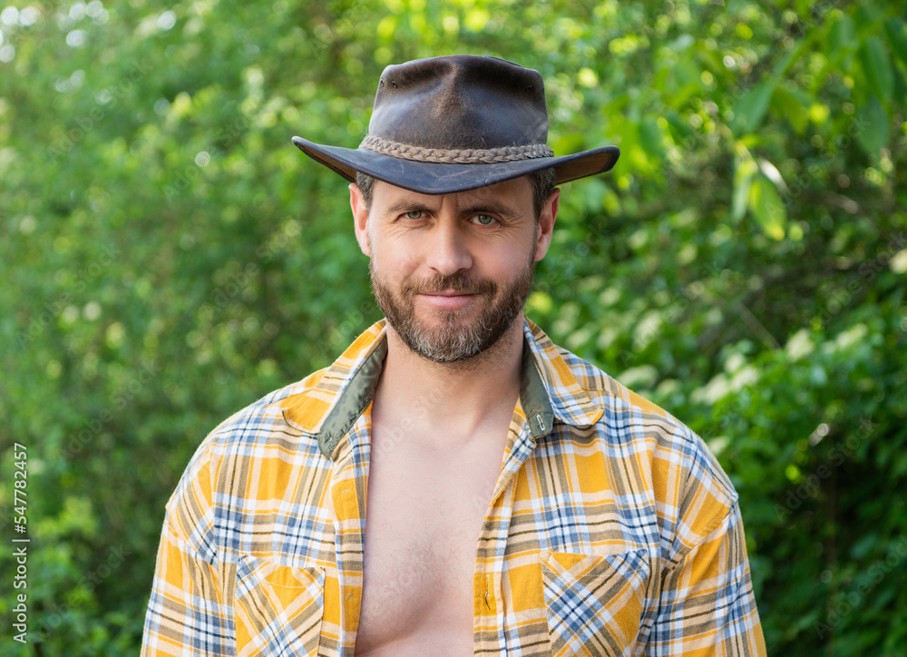 smiling macho man in cowboy hat. macho man in checkered shirt. western macho man wearing hat