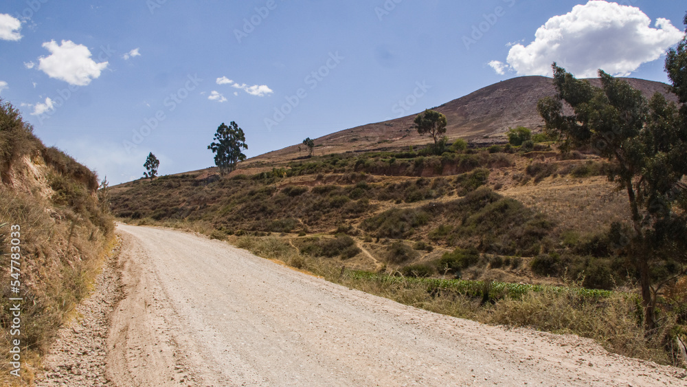 Dry andean landscape with dirt road going up with mountain next to it Cusco, Peru