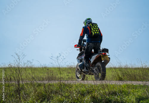motor cyclist (biker) riding an off-road motorbike along a stone track, Wiltshire UK
