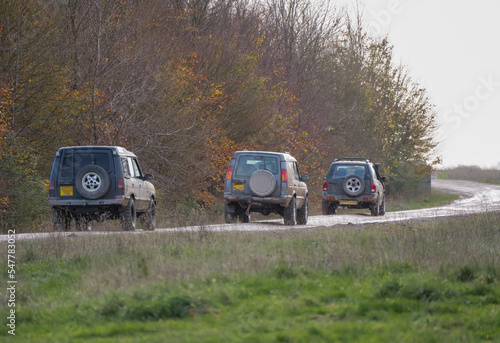 three modified off road 4x4 vehicles driving along a mud track, Wilts UK