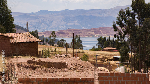 Haypo lake in the distance behind brick and adobe buildings, Maras, Peru 