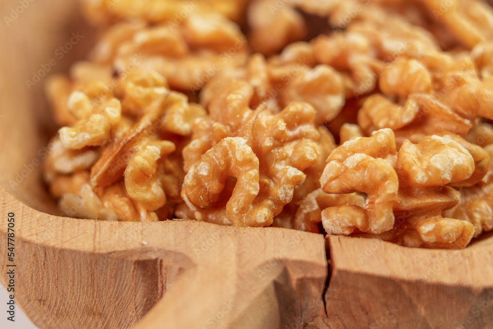 Peeled walnut cores in a cracked rustic wooden bowl. Dry nuts kernels Peeled walnut cores in a cracked rustic wooden bowl. Dry nuts kernels