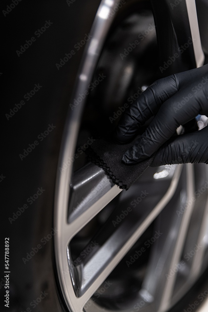 Car detailing studio employee applies a ceramic coating to the rim of the car