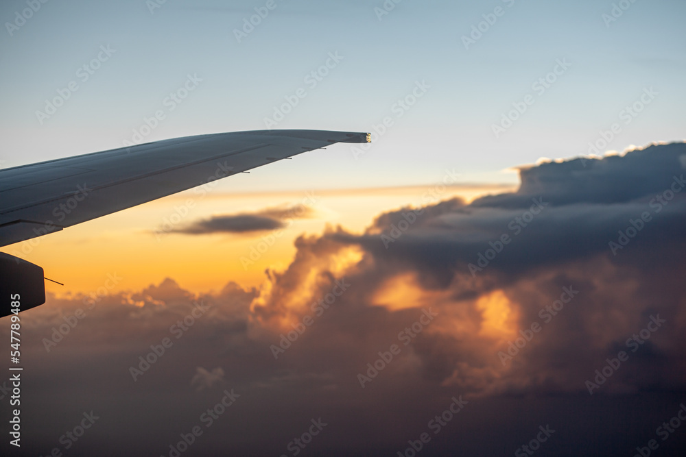 Airplane flight at sunset or dawn. Aircraft's wing and land seen through the illuminator. View from the window of the plane. Airplane, Aircraft. Traveling by air. Airplane flight at sunset or dawn. Aircraft's wing and land seen through the illuminator. View from the window of the plane. Airplane, Aircraft. Traveling by air.