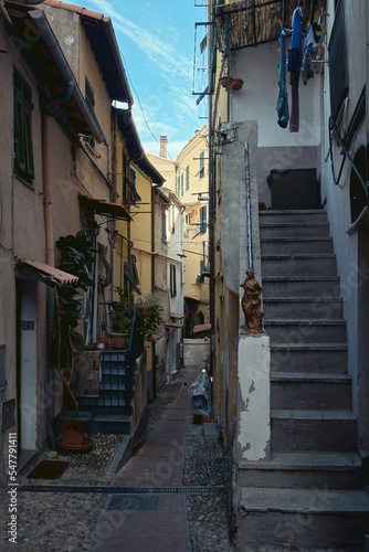 A narrow street with colourful buildings and laundry hung to dry in an old town in Europe. Ventimiglia, Italy © George
