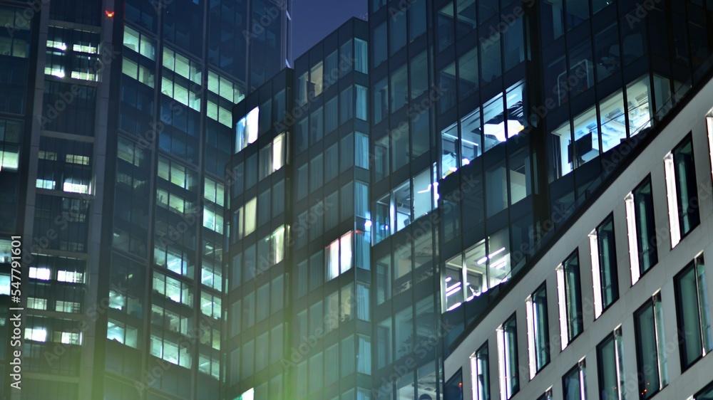 Modern office building in city at the night. View on illuminated offices of a corporate building. Blinking light in window of the multi-storey building of glass and steel. Long exposure at night Modern office building in city at the night. View on illuminated offices of a corporate building. Blinking light in window of the multi-storey building of glass and steel. Long exposure at night