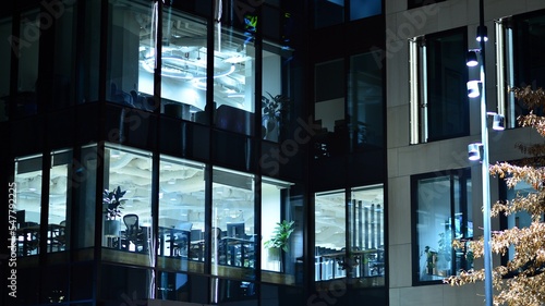 Modern office building in city at the night. View on illuminated offices of a corporate building. Blinking light in window of the multi-storey building of glass and steel. Long exposure at night