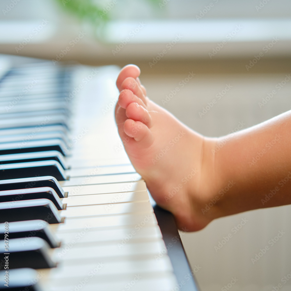 Toddler baby foot on electric piano keys, close-up. Child feet lie on an  electronic portable piano. Kid boy age one year four months Stock Photo |  Adobe Stock