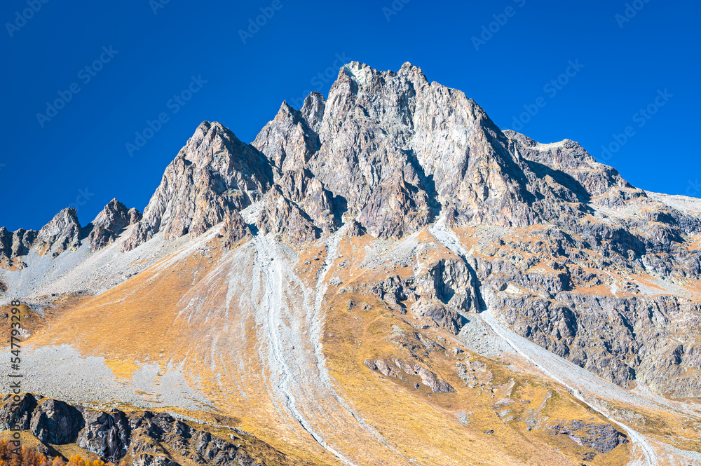 Beautiful nature image of a mountain peak with talus slope underneath in Maloja region, Upper Engadine, Switzerland on a sunny day in October.