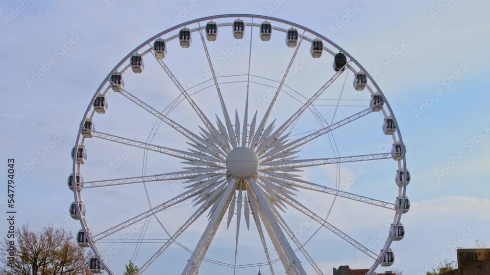 Attraction in the park a ferris wheel against a blue sky with clouds Attraction in the park a ferris wheel against a blue sky with clouds