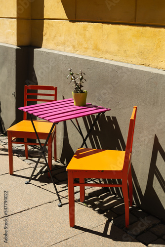 Two welcoming and colorful chairs by the pink table in a sunny summer day in the trendy street café, Helsinki, Finland 