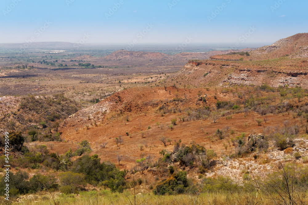 Landscape of Madagascar, typical scenery of the Malagasy countryside with the rice fields, hills and valleys, small simple houses and dry meadows. Devastated environment with great erosion