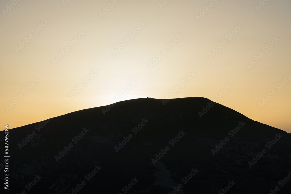 Silhouette of a large rocky mountain in the light of the setting sun