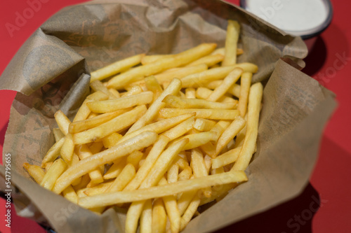 Plate of french fries. Paper cone or paper bag with chips. 