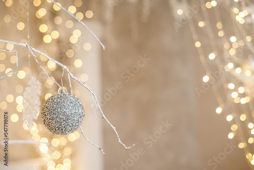 A white Christmas tree is decorated with silver plastic toys. Bright festive decoration for the new year