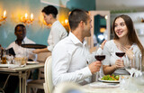 Young couple having romantic dinner and drinking red wine at restaurant