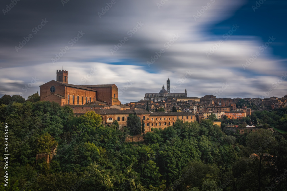 Beautiful panoramic view of the historic city of Siena at daytime with an amazing cloudscape on an idyllic autumn evening, Tuscany, Italy. Long exposure picture. October 2022
