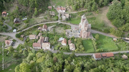 Panoramic aerial drone view of the famous abbey of Murbach and its village in the heart of Florival valley near Guebwiller (Alsace, France), in the middle of the mountain forest, a summer day photo