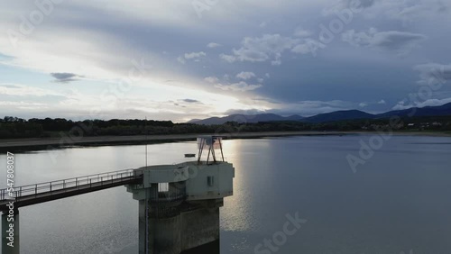 Water intake tower of the Michelbach lake dam (Upper-Rhine, Alsace, France), in drought weather in summer, with a very low water level, at sunset, with the mountains in the background photo