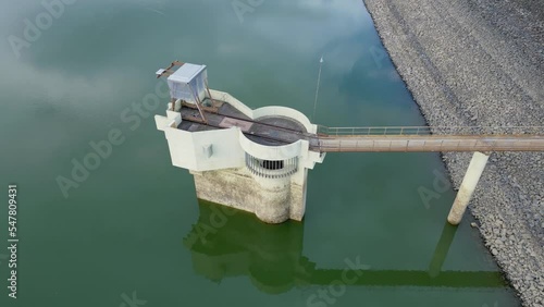 Water intake tower of the Michelbach lake dam (Upper-Rhine, Alsace, France) in 360 degrees rotation aerial drone close view for all faces, by drought weather in summer with a very low water level photo