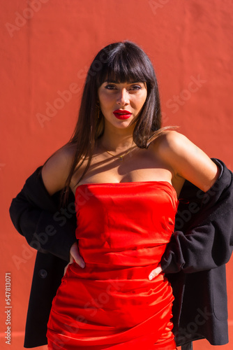 Brunette girl in a portrait on a red background, red dress, provocative girl