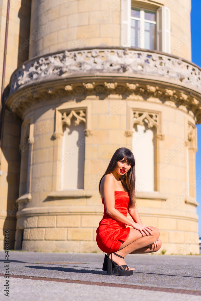 Fototapeta premium Portrait in red dress in beautiful castle, attractive girl, crouching portrait