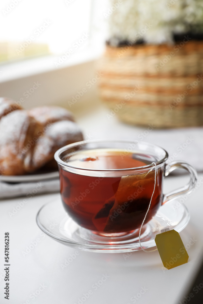 Tea bag in glass cup on white windowsill Tea bag in glass cup on white windowsill