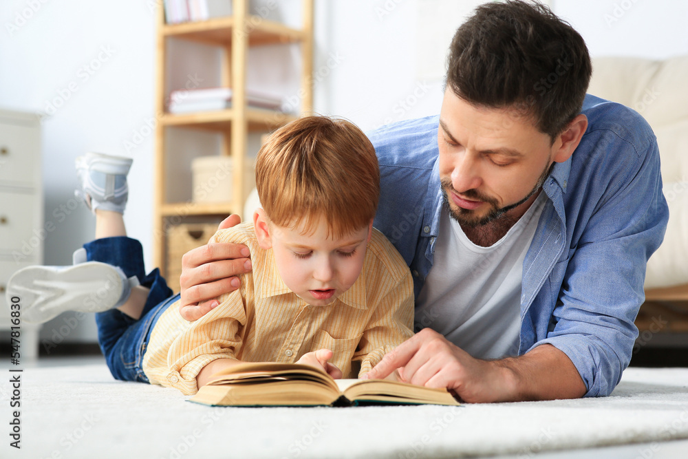 Father reading book with his son on floor in living room at home Father reading book with his son on floor in living room at home