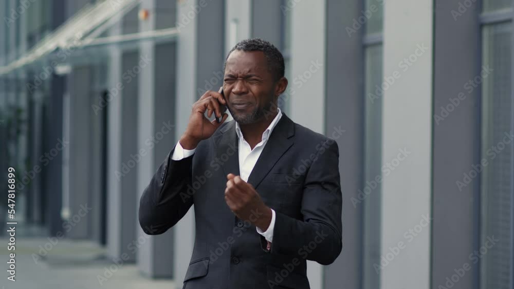 Irritated african american businessman resolving problems on distance, emotionally quarrelling with partners on phone Irritated african american businessman resolving problems on distance, emotionally quarrelling with partners on phone