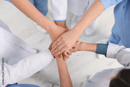 Team of medical doctors putting hands together indoors, above view