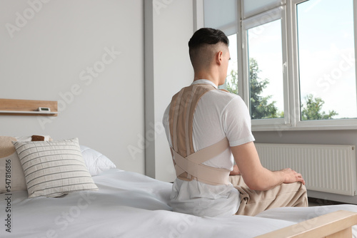 Man with orthopedic corset sitting in bedroom