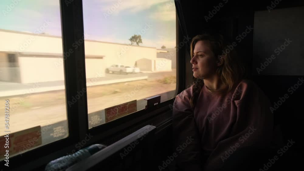 Woman on Train Looks Peacefully Out Window as Terrain Rolls By Woman on Train Looks Peacefully Out Window as Terrain Rolls By