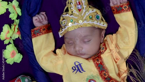 newborn baby boy in krishna dressed with props at swing from unique angle in different expression photo