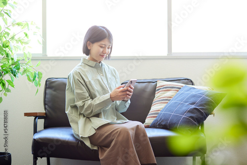 リビングのソファーでくつろぐ若い日本人女性 #547818031