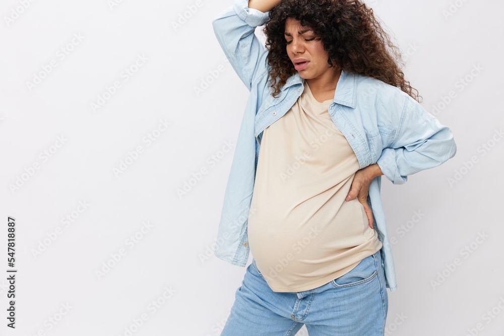 Pregnant woman fatigue back pain and headache on white isolated background in t-shirt with blue shirt Pregnant woman fatigue back pain and headache on white isolated background in t-shirt with blue shirt