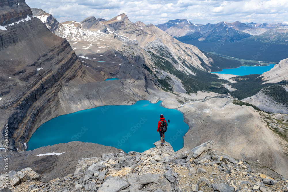 Hiker standing on a cliff above blue glacial lake above Bow Lake, Banff National Park, Alberta, Canada.
