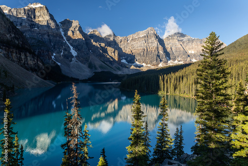Early morning view of Moraine Lake with trees in foreground, Banff National Park, Alberta, Canada.