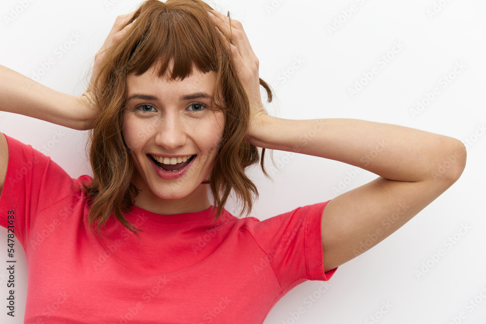 a sweet, happy, funny woman in a red T-shirt with red hair color stands on a white background and holds her head with her hands, smiling happily a sweet, happy, funny woman in a red T-shirt with red hair color stands on a white background and holds her head with her hands, smiling happily
