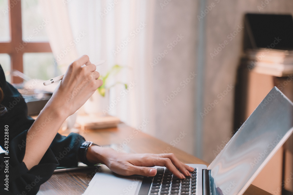 A young businesswoman is working online by internet with a phone and laptop at a cafe. A young businesswoman is working online by internet with a phone and laptop at a cafe.