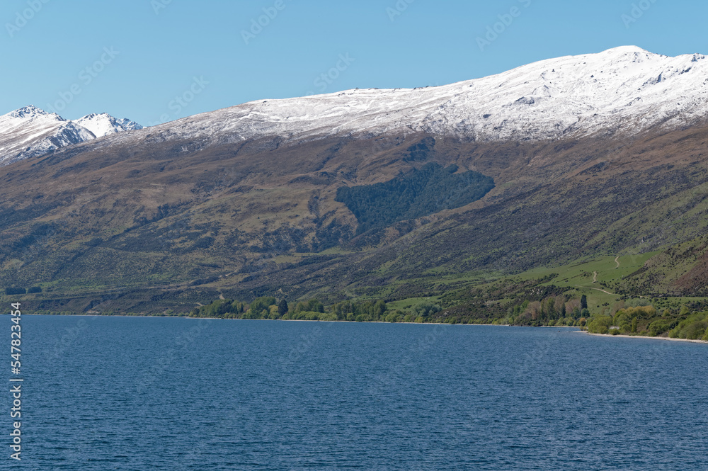 Lake Whakatipu sits in front of snow dusted mountains in New Zealand.
