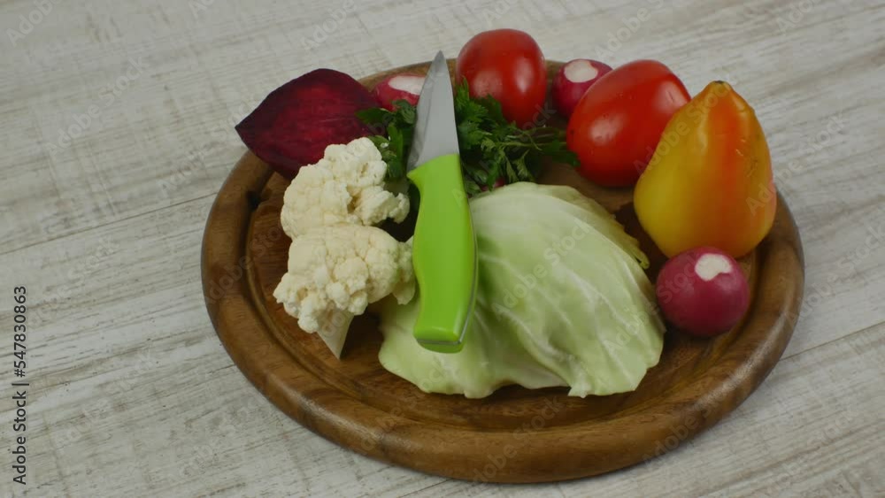 Round brown wooden cutting board with beautifully laid out fresh vegetables. Vegetable set for making fresh raw healthy veggie salad. Healthy lifestyle Round brown wooden cutting board with beautifully laid out fresh vegetables. Vegetable set for making fresh raw healthy veggie salad. Healthy lifestyle